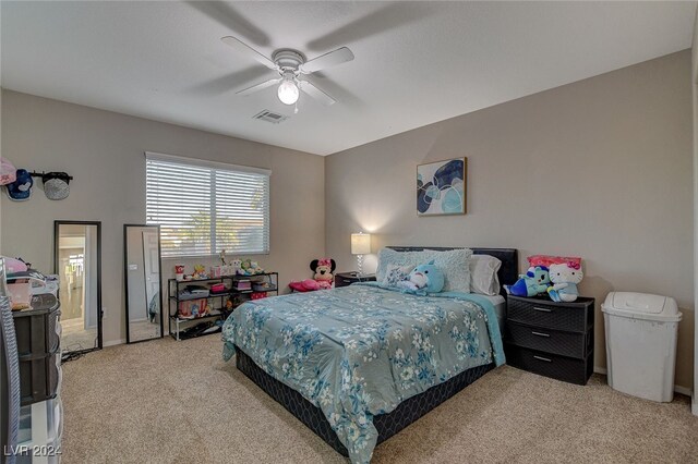 bedroom featuring light carpet, ensuite bathroom, and ceiling fan