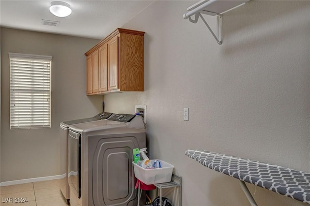 laundry area featuring baseboards, light tile patterned floors, visible vents, washing machine and clothes dryer, and cabinet space