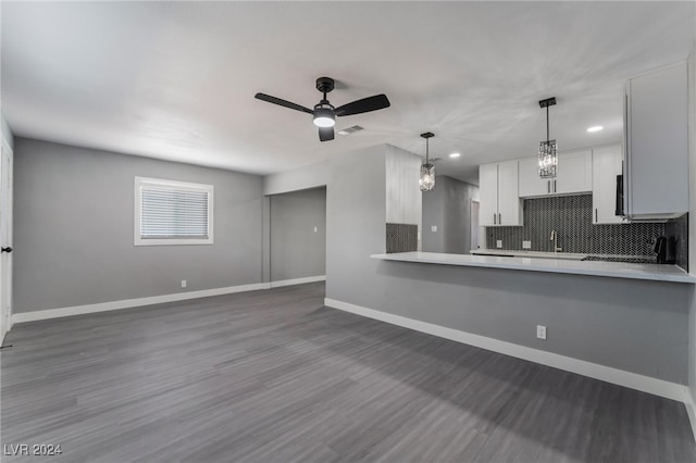 kitchen featuring ceiling fan, dark hardwood / wood-style flooring, kitchen peninsula, white cabinetry, and backsplash