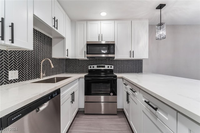 kitchen with white cabinets, sink, pendant lighting, light hardwood / wood-style flooring, and appliances with stainless steel finishes