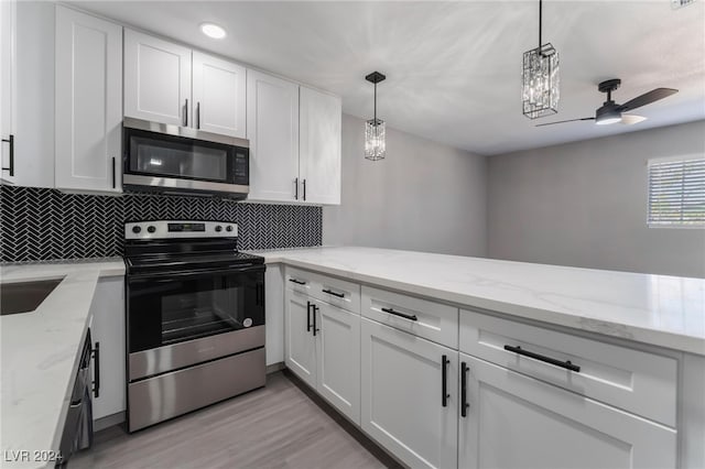 kitchen with light stone counters, white cabinets, stainless steel appliances, and light hardwood / wood-style floors