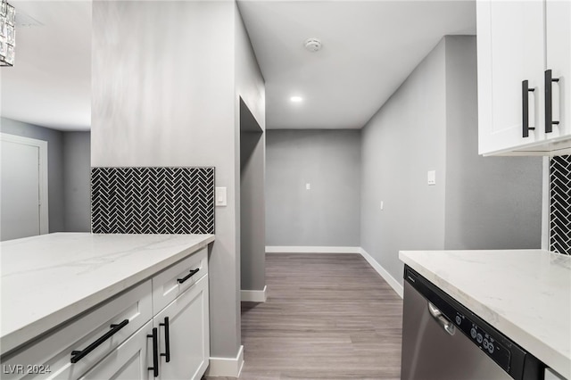 kitchen with dishwasher, light stone countertops, light hardwood / wood-style floors, and white cabinetry