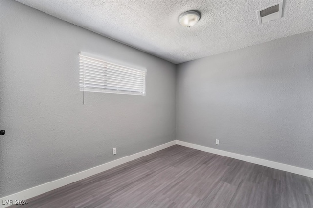 unfurnished room featuring a textured ceiling and dark hardwood / wood-style floors