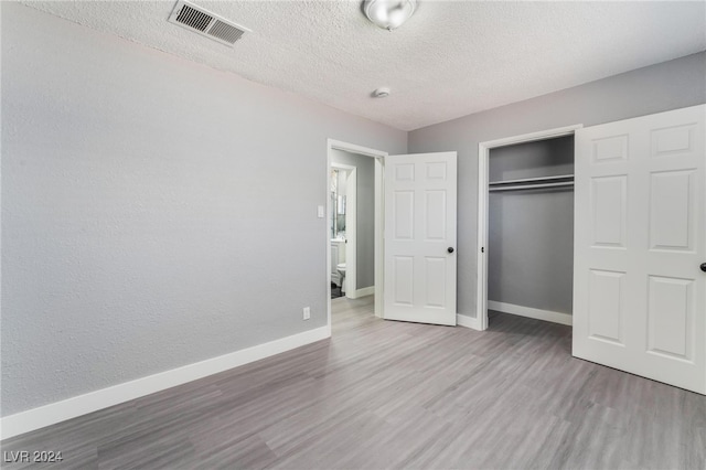 unfurnished bedroom featuring a textured ceiling, a closet, and hardwood / wood-style floors