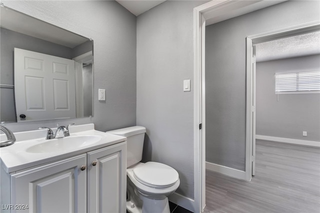 bathroom featuring wood-type flooring, vanity, toilet, and a textured ceiling