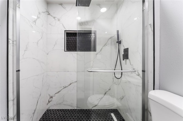 bathroom with a shower with shower door and toilet