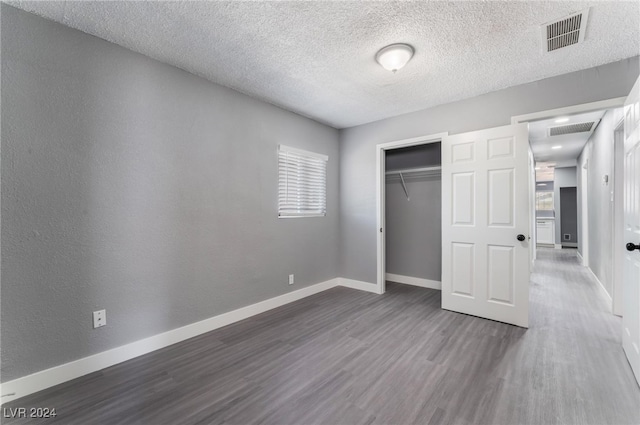 unfurnished bedroom with a textured ceiling, a closet, and dark wood-type flooring