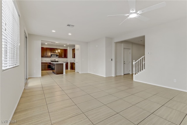 unfurnished living room with light tile patterned flooring and ceiling fan