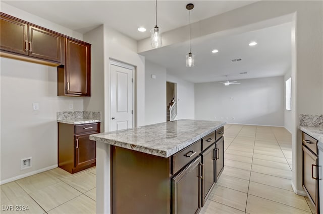 kitchen featuring light stone counters, a kitchen island, hanging light fixtures, and ceiling fan