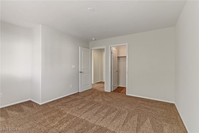 unfurnished bedroom with a walk in closet, a closet, and carpet