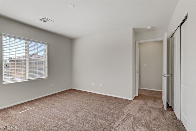 unfurnished bedroom featuring a closet and light colored carpet