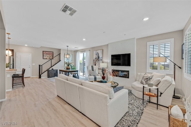 living room with light hardwood / wood-style floors, an inviting chandelier, and a fireplace