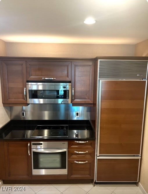 kitchen with dark brown cabinets, appliances with stainless steel finishes, and light tile patterned floors