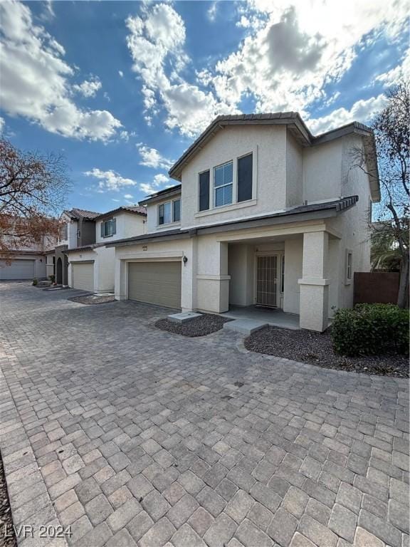 view of front of home featuring an attached garage, decorative driveway, and stucco siding
