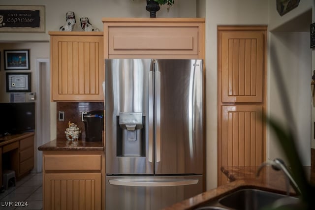 kitchen featuring dark stone countertops, stainless steel fridge with ice dispenser, tile patterned floors, and light brown cabinets