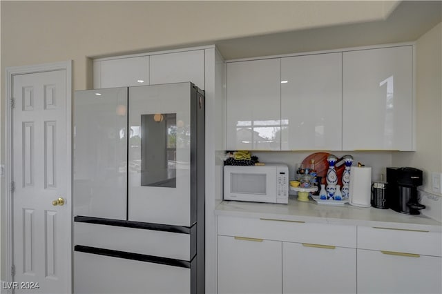 kitchen featuring fridge and white cabinets