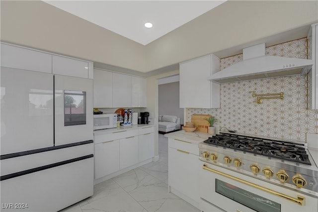 kitchen featuring high end stainless steel range, custom range hood, light stone countertops, white cabinets, and tasteful backsplash