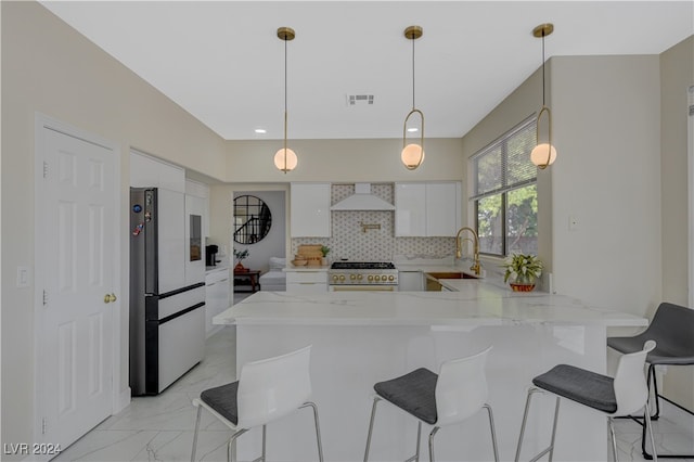 kitchen featuring hanging light fixtures, kitchen peninsula, high end stainless steel range oven, refrigerator, and white cabinetry