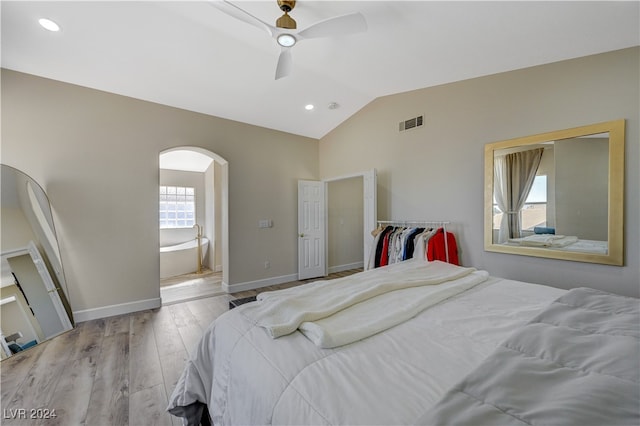 bedroom with lofted ceiling, connected bathroom, light wood-type flooring, and ceiling fan