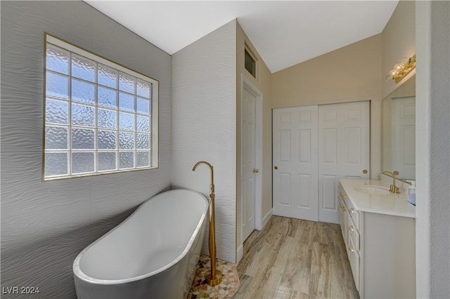 bathroom featuring vanity, lofted ceiling, a tub, and wood-type flooring