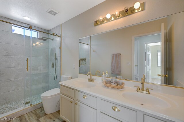 bathroom with toilet, a shower with shower door, hardwood / wood-style floors, vanity, and a textured ceiling