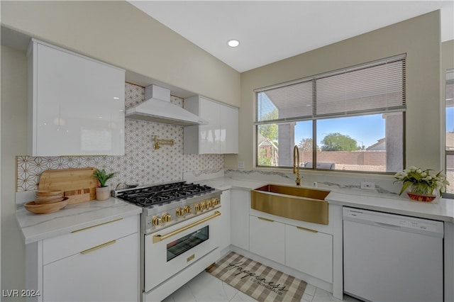 kitchen featuring white appliances, sink, backsplash, white cabinets, and premium range hood