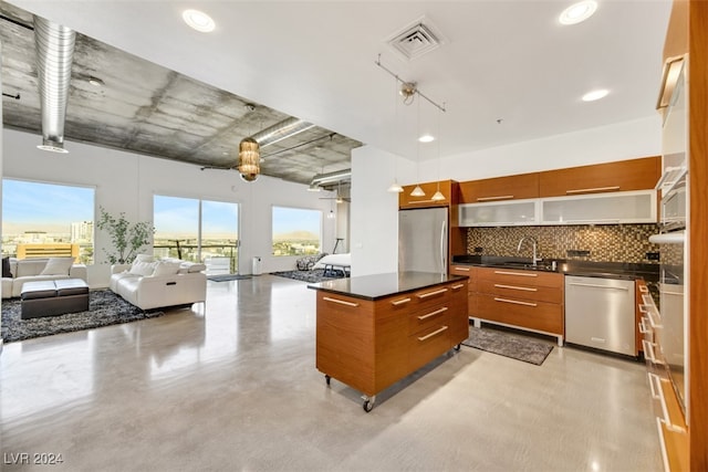 kitchen with sink, a kitchen island, decorative light fixtures, stainless steel appliances, and decorative backsplash