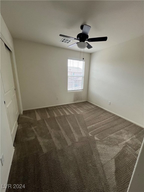 unfurnished bedroom featuring dark colored carpet, ceiling fan, and a closet