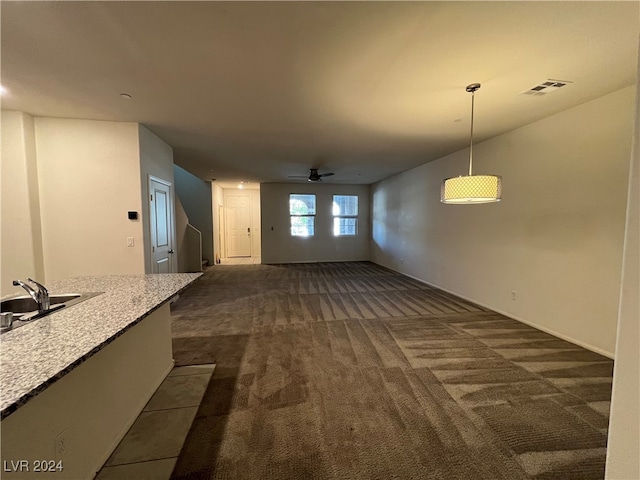 unfurnished living room featuring dark colored carpet, sink, and ceiling fan