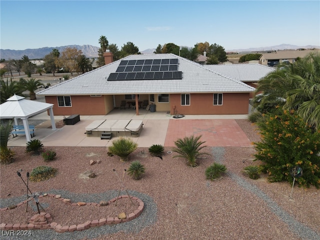 back of property featuring a gazebo, a mountain view, a patio area, and solar panels