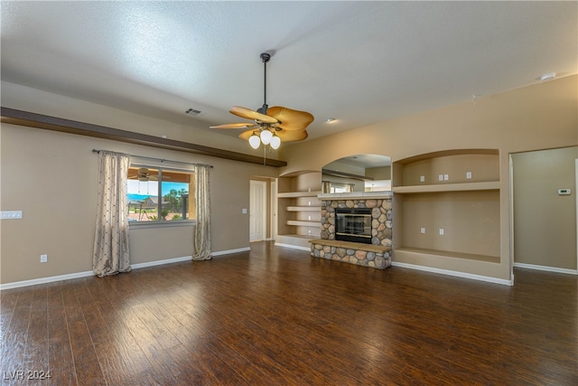 unfurnished living room with built in shelves, ceiling fan, a fireplace, and dark hardwood / wood-style flooring