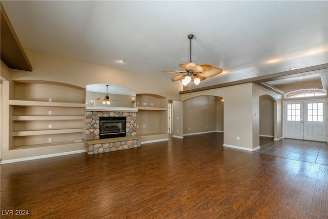 unfurnished living room featuring dark hardwood / wood-style flooring, a fireplace, built in features, and ceiling fan