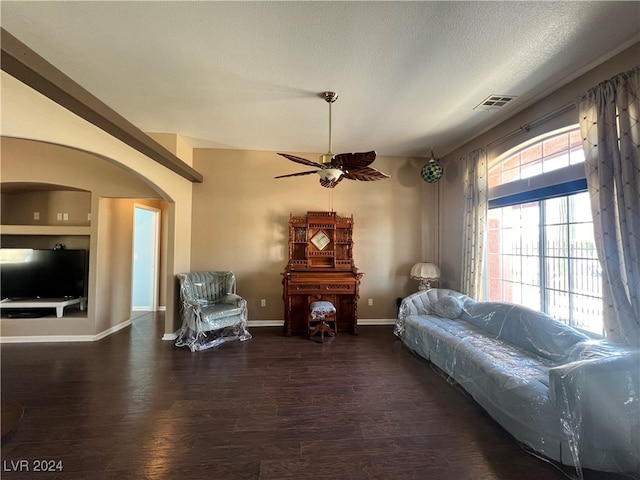 living area featuring built in shelves, a textured ceiling, dark hardwood / wood-style floors, and ceiling fan