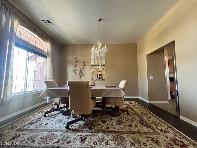 dining room with dark hardwood / wood-style floors and an inviting chandelier