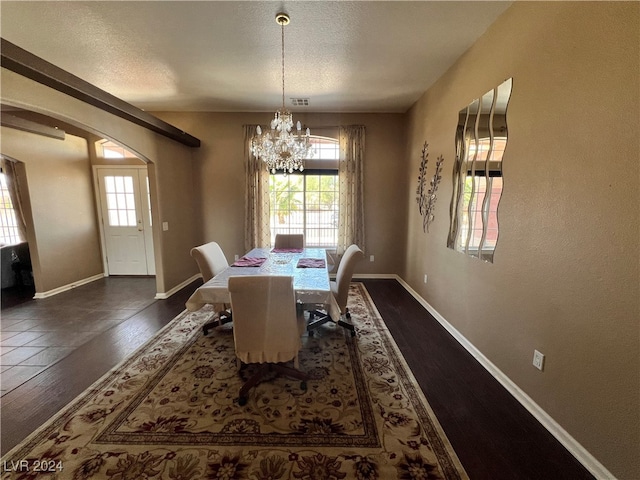 dining area featuring dark hardwood / wood-style flooring, a textured ceiling, and an inviting chandelier