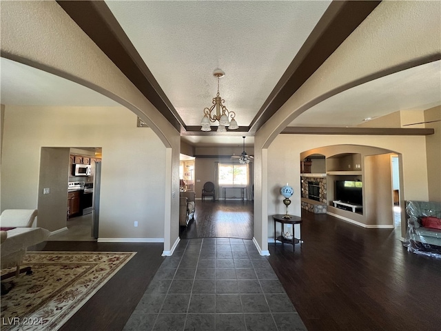 entrance foyer featuring dark hardwood / wood-style floors, a fireplace, ceiling fan with notable chandelier, and a textured ceiling