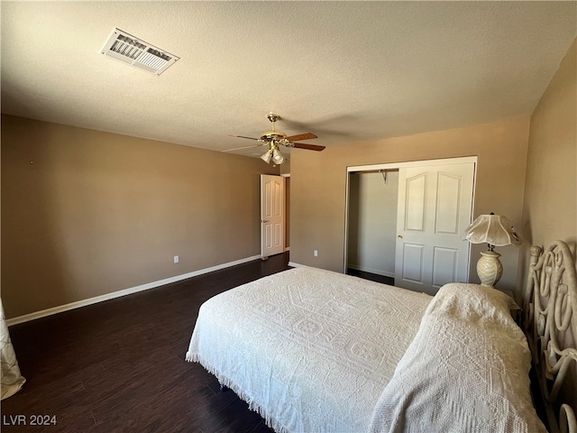 bedroom with dark hardwood / wood-style floors, a textured ceiling, a closet, and ceiling fan