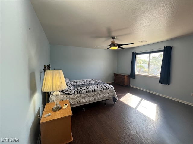 bedroom with dark wood-type flooring, ceiling fan, and a textured ceiling