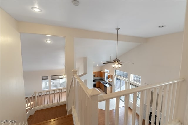 staircase with ceiling fan, hardwood / wood-style flooring, and lofted ceiling