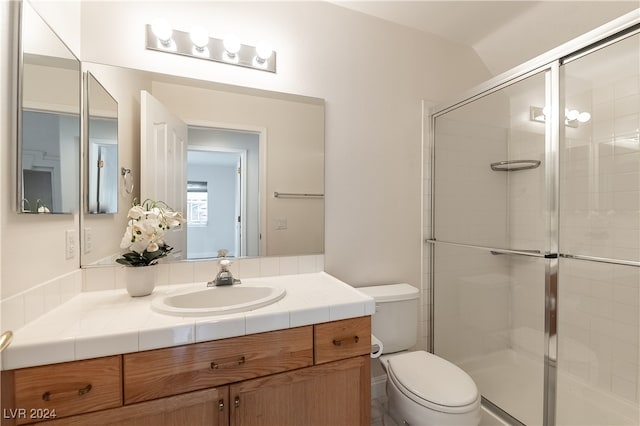 bathroom with vaulted ceiling, vanity, toilet, and a shower with door