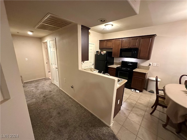 kitchen with kitchen peninsula, black appliances, dark brown cabinetry, and light carpet