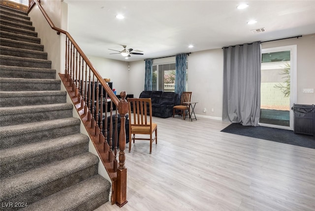 staircase with hardwood / wood-style flooring and ceiling fan