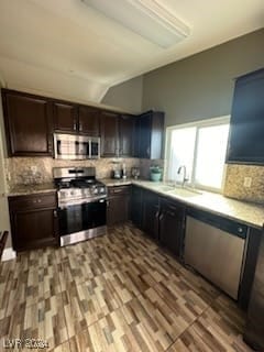 kitchen with appliances with stainless steel finishes, sink, decorative backsplash, and hardwood / wood-style floors