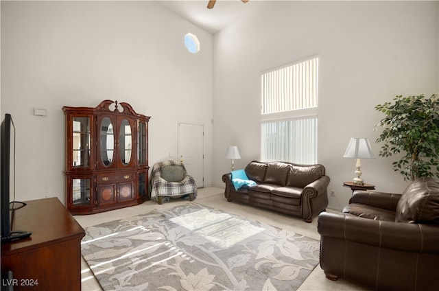 living room featuring a high ceiling, light carpet, and ceiling fan