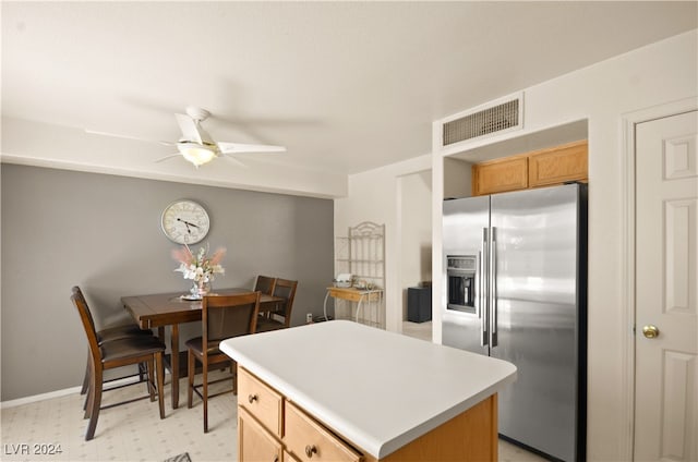 kitchen with stainless steel refrigerator with ice dispenser, a center island, and ceiling fan