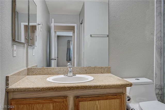 bathroom featuring a textured wall, vanity, and toilet