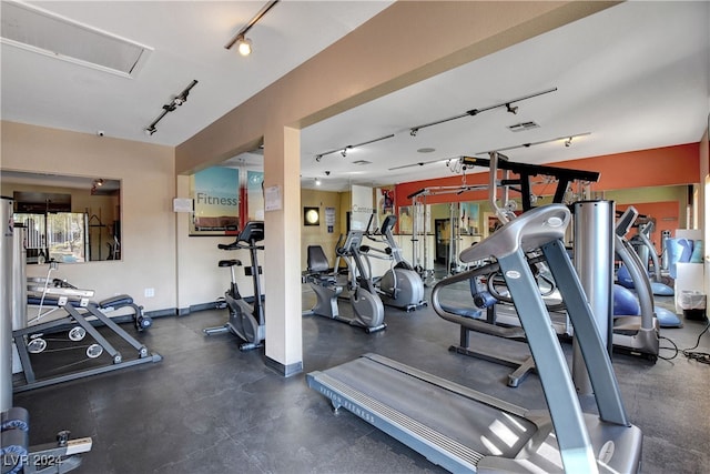 exercise room featuring rail lighting and baseboards