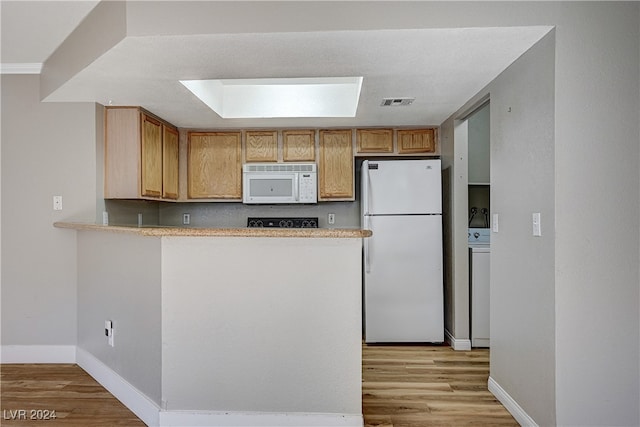 kitchen featuring washer / clothes dryer, white appliances, light wood-style flooring, and a peninsula