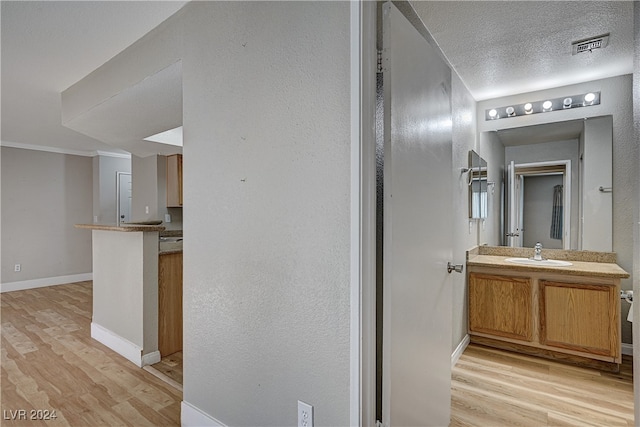 bathroom featuring a textured ceiling, baseboards, wood finished floors, and vanity