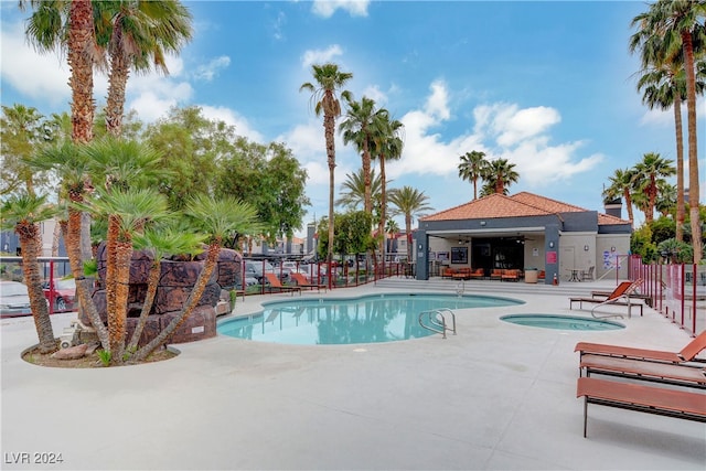 pool with a community hot tub, a patio area, and fence